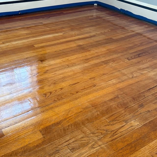 Golden oak floor freshly recoated — wet coat just applied